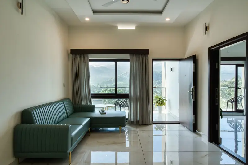 Lounge with a teal sofa and windows onto the hills