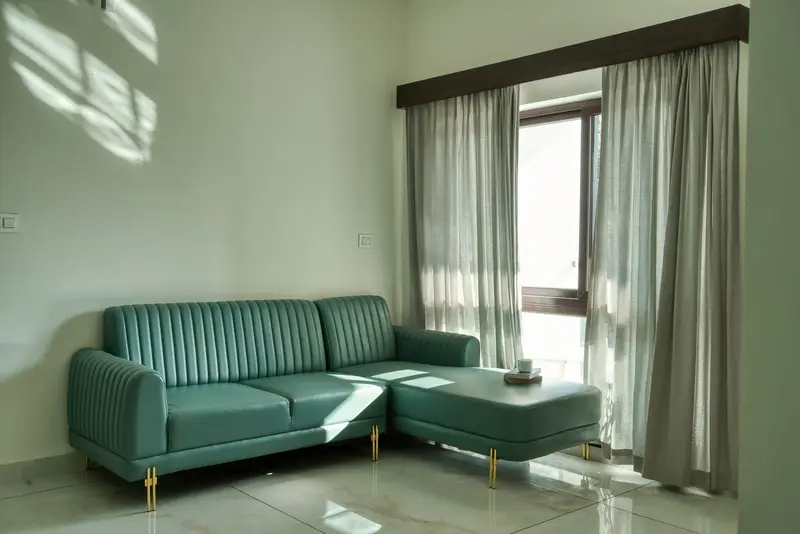 Bright lounge with a teal sofa and tall windows